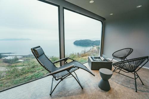 two chairs and a table in a room with large windows at HARIO Beach Walk in Sakihario