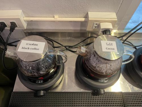 two coffee pots sitting on top of a counter at Alongkorn hotel by SB in Samut Songkhram