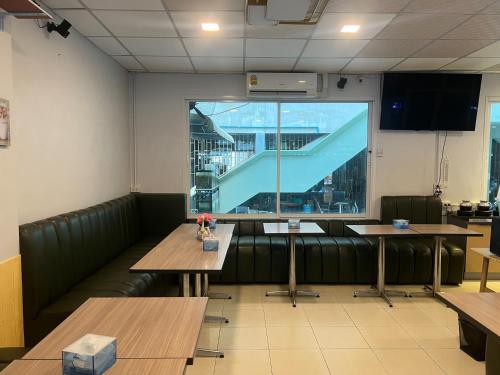 a restaurant with wooden tables and a large window at Alongkorn hotel by SB in Samut Songkhram