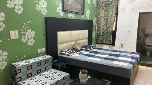 1 dormitorio con 1 cama y una pared verde con flores en Hotel Krishna Palace, en Nueva Delhi