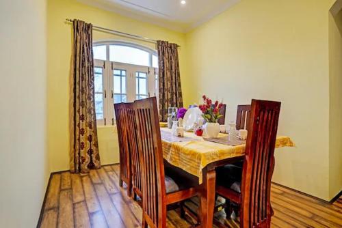 a dining room with a table with chairs and a window at Lit Homestay in Srinagar