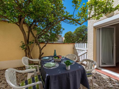 une table bleue avec des chaises blanches et un arbre dans l'établissement Apartment Zodiaques 1 by Interhome, au Barcarès