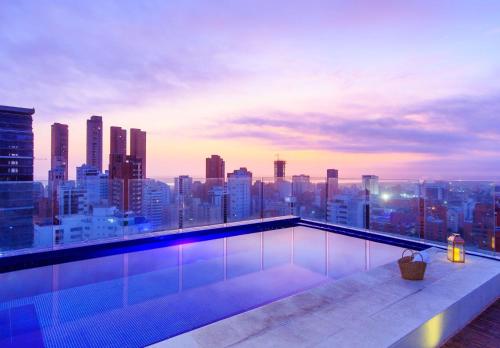 a rooftop swimming pool with a view of a city at NH Collection Royal Smartsuites in Barranquilla
