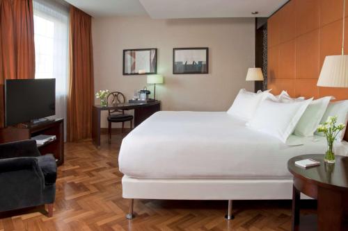 una camera d'albergo con un grande letto e una TV di NH Collection Buenos Aires Lancaster a Buenos Aires