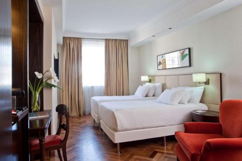 una camera d'albergo con un grande letto bianco e una sedia di NH Collection Buenos Aires Lancaster a Buenos Aires