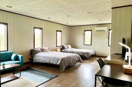 1 dormitorio con 2 camas, sofá y escritorio en 百合ヶ浜ビーチハウス, en Furusato