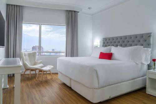 a white bedroom with a large bed and a window at NH Collection Plaza Santiago in Santiago