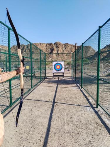 a person holding a bow and arrows in front of a target at Dibba Mountain Park Resort in Fujairah