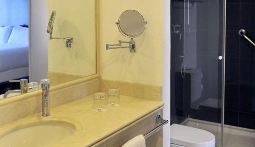W łazience znajduje się umywalka, lustro i toaleta. w obiekcie NH Ciudad de Santiago w mieście Santiago