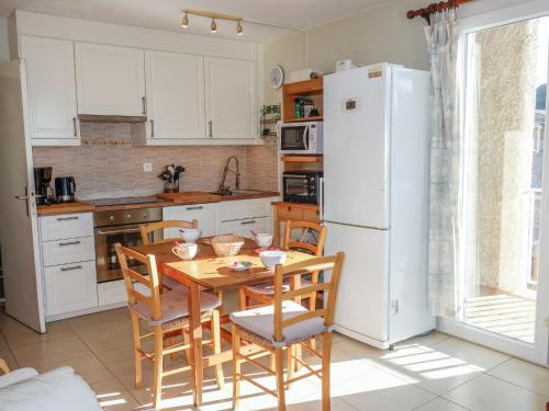 une cuisine avec une table et des chaises et un réfrigérateur blanc dans l'établissement Apartment Les Aigues Marines-29 by Interhome, à Saint-Cyr-sur-Mer