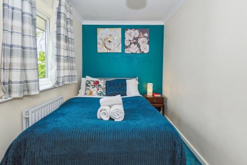 Un dormitorio azul con una cama con toallas. en Global Boutique Relocation Ltd 2Bed -free parking en Hatfield