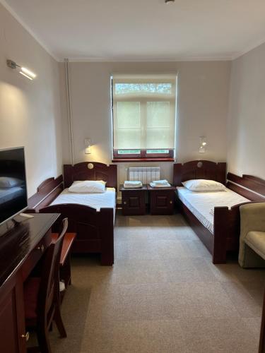 a room with two beds and a flat screen tv at Konačište Osmica in Mokra Gora
