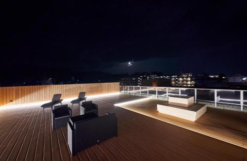 eine Terrasse mit 2 Stühlen und Blick auf die Stadt in der Nacht in der Unterkunft Sarusawaike Yoshidaya in Nara