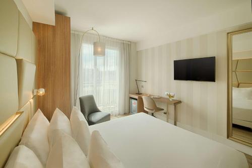 um quarto de hotel com uma cama branca e uma secretária em NH Collection Roma Centro em Roma