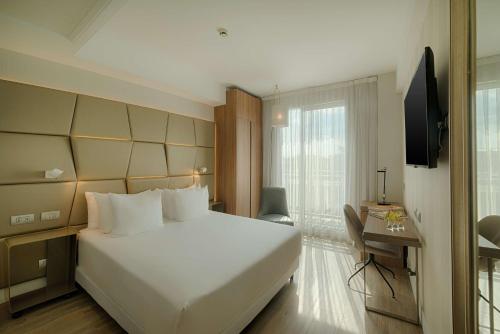 una camera da letto con un grande letto bianco e una finestra di NH Collection Roma Centro a Roma
