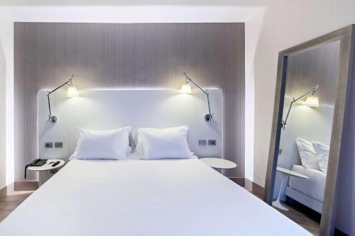 a bedroom with a large white bed with two lamps at NH Milano Congress Centre in Assago