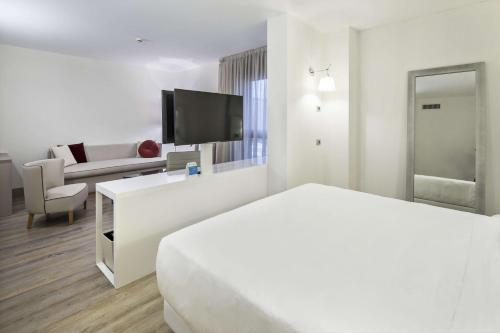 a white hotel room with a bed and a tv at NH Milano Congress Centre in Assago