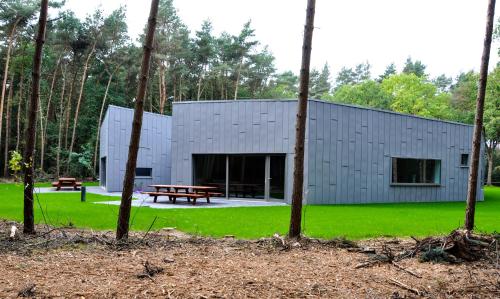 un edificio gris con una mesa de picnic en el bosque en Twinstone Lodge en Genk