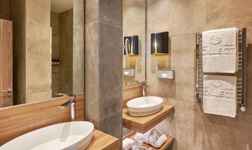 uma casa de banho com dois lavatórios e um WC em NH Collection Madrid Gran Vía em Madrid