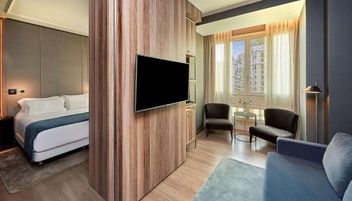 um quarto de hotel com uma cama e uma televisão de ecrã plano em NH Collection Madrid Gran Vía em Madrid