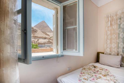 开罗Villa Khufu Pyramids Hotel的房间里有一张床，窗户对着金字塔