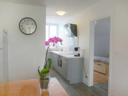 une cuisine avec une horloge et un vase avec des fleurs roses dans l'établissement Apartment Pierre Legavre by Interhome, à Saint-Malo
