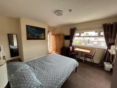 a bedroom with a bed and a desk and a window at Blue Boar Inn in Atherstone
