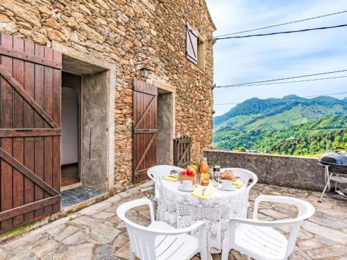 a table and chairs on a patio with mountains in the background at Holiday Home Casa Piana by Interhome in San-Giovanni-di-Moriani