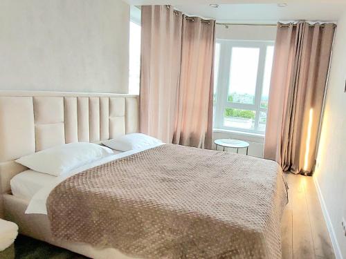 a bedroom with a large bed and a window at Уютные апартаменты в новострое на Ботанике in Chişinău