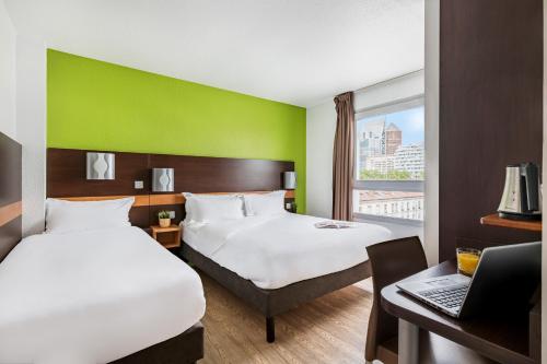 a hotel room with two beds and a desk with a laptop at Première Classe Lyon Centre Gare Part Dieu in Lyon