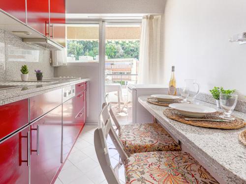 une cuisine avec des armoires rouges et une table avec des chaises dans l'établissement Apartment L'Antonia by Interhome, à Roquebrune-Cap-Martin
