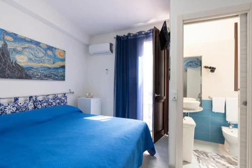 a bedroom with a blue bed and a bathroom at Charming House in Castellammare del Golfo with Balcony in Castellammare del Golfo