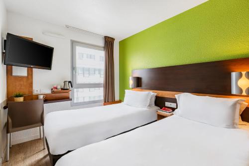 a hotel room with two beds and a flat screen tv at Première Classe Lyon Centre Gare Part Dieu in Lyon