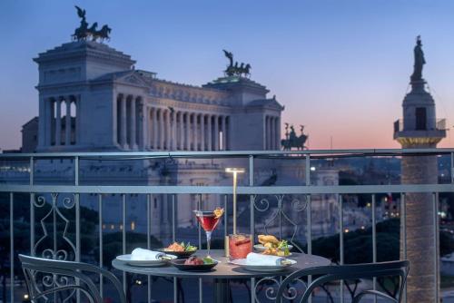 einen Tisch mit Teller mit Speisen auf dem Balkon in der Unterkunft NH Collection Roma Fori Imperiali in Rom