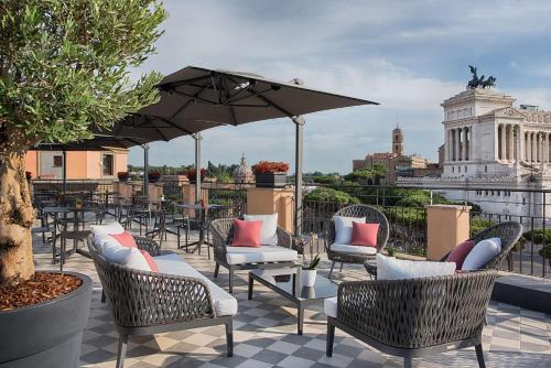 eine Terrasse mit Stühlen und einem Sonnenschirm auf dem Dach in der Unterkunft NH Collection Roma Fori Imperiali in Rom