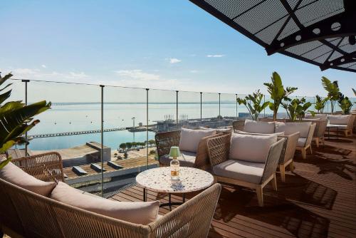 um pátio com cadeiras e mesas e vista para o oceano em Tivoli Oriente Lisboa Hotel em Lisboa