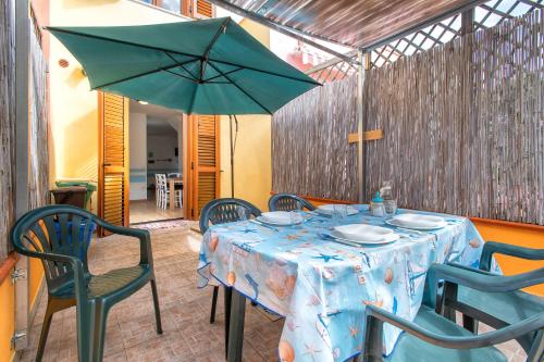 a table with a blue table cloth and a green umbrella at Holiday Cala Sant'andrea in Stintino