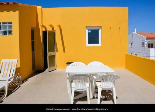 a patio with a white table and chairs on a yellow building at Blife Faro Beach Hostel & Rooms in Faro