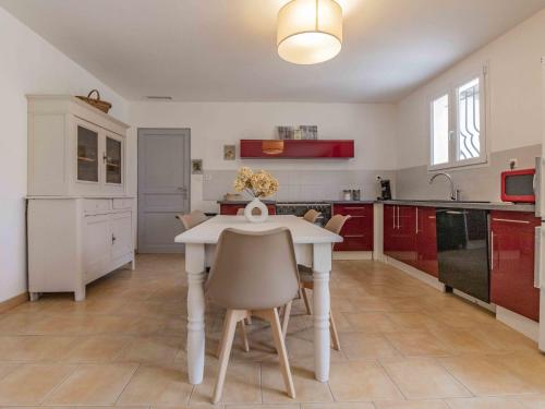 uma cozinha com armários vermelhos e uma mesa e cadeiras brancas em Holiday Home L' amandier by Interhome em Saint-Didier