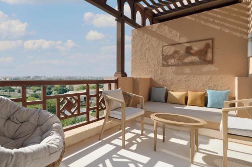 a patio with a couch and chairs on a balcony at InterContinental Durrat Al Riyadh Resort & Spa by IHG in Riyadh