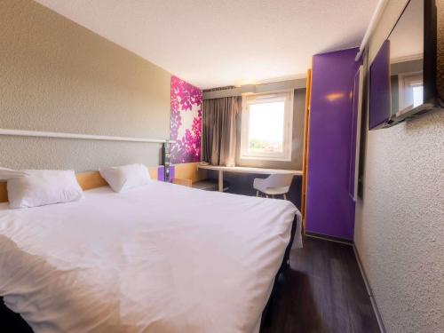 a hotel room with a white bed and a window at ibis Vesoul in Vesoul