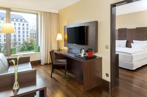 a hotel room with a bed and a desk with a television at NH Collection Dresden Altmarkt in Dresden
