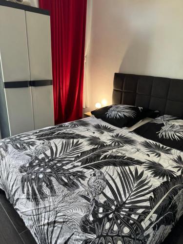 a bedroom with a bed with a black and white comforter at SKYS LOCATION PAKEHINA in Schœlcher