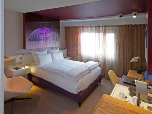 una camera d'albergo con un grande letto e una scrivania di Pullman Eindhoven Cocagne a Eindhoven