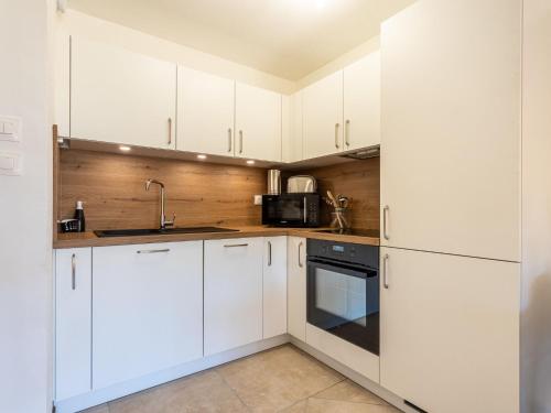 une cuisine avec des armoires blanches et un micro-ondes dans l'établissement Apartment Les Regates-5 by Interhome, à Hyères