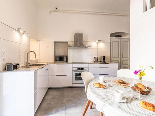 une cuisine avec des placards blancs et une table avec de la nourriture. dans l'établissement Apartment Casa Grandval by Interhome, à Ajaccio
