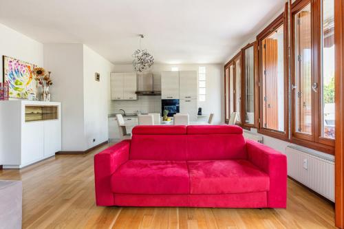 a red couch in a living room with a kitchen at Arcave Luxury Apartment in Sirmione