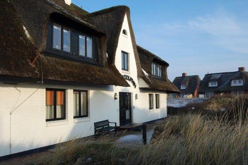 a house with a thatched roof with a bench in front at Lazy-Dolphin-Wohnung-3 in Rantum