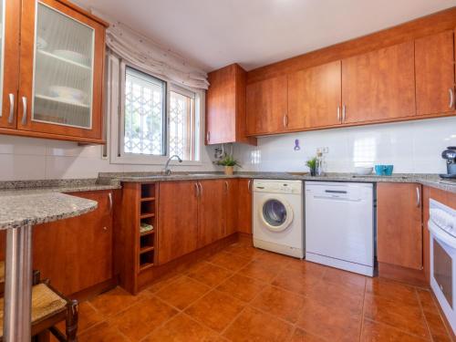 a kitchen with wooden cabinets and a washer and dryer at Holiday Home Cal 5inc by Interhome in Creixell