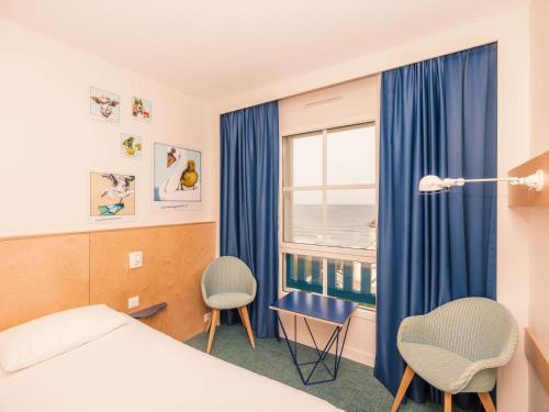 a hotel room with a bed and chairs and a window at ibis Styles Deauville Villers Plage in Villers-sur-Mer
